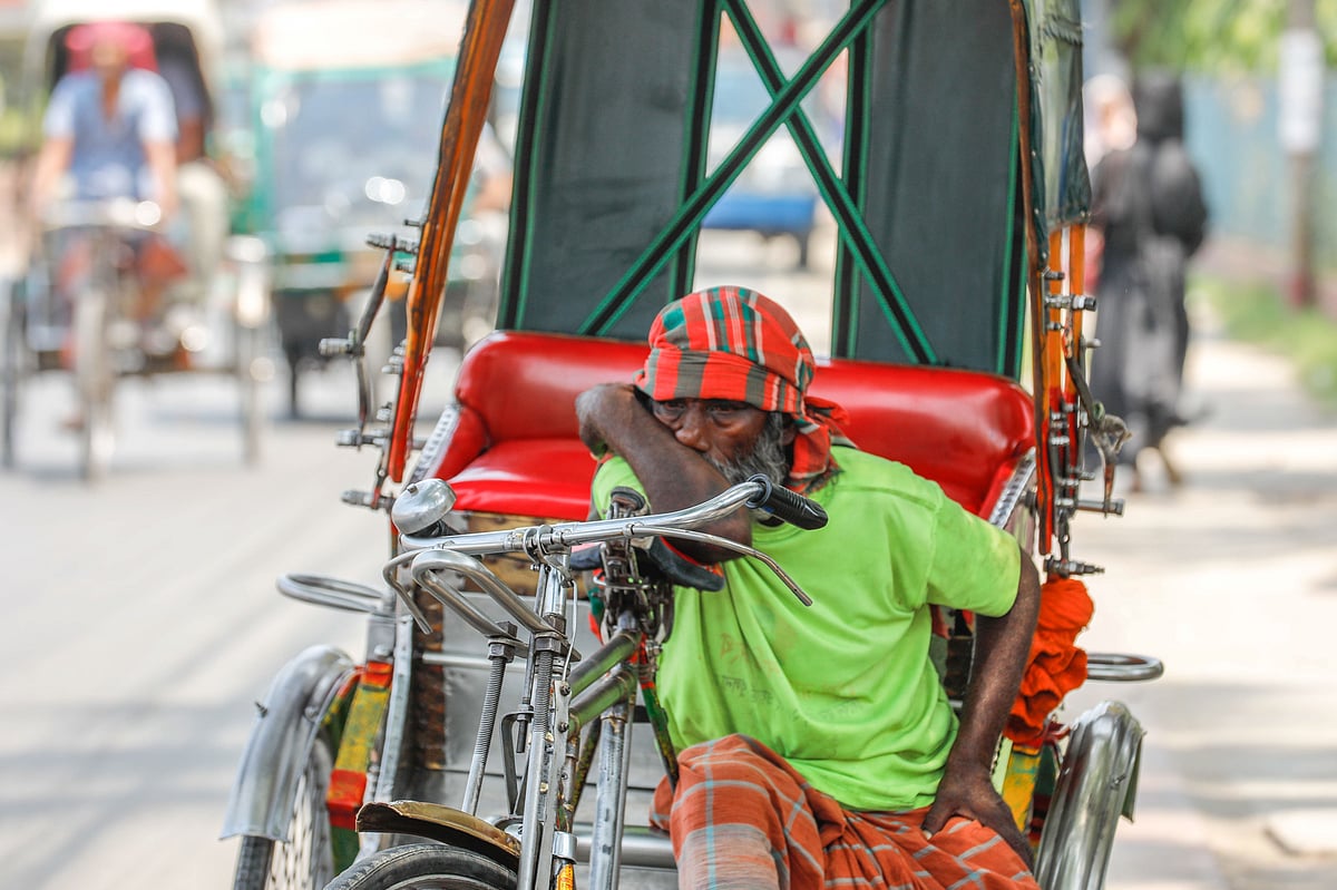 রোদে রিকশা চালিয়ে হাঁপিয়ে ওঠা এক চালক বিশ্রাম নিচ্ছেন। 