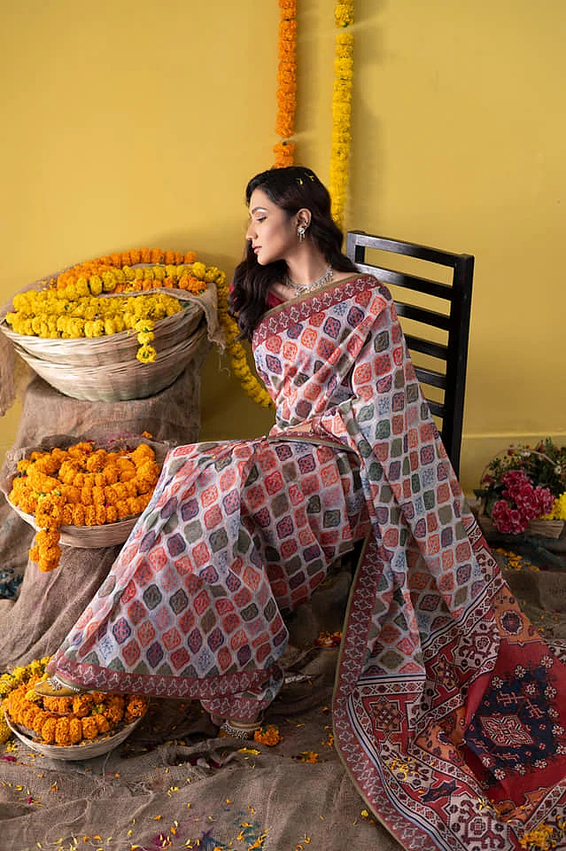 সাদা কটন ব্লেন্ডের সিল্কে তুর্কি ঘরানার নানা রঙের মোটিফ। সাদা-লালের মধ্যে থেকেও বেশ আলাদা আমেজ দিচ্ছে শাড়িটি