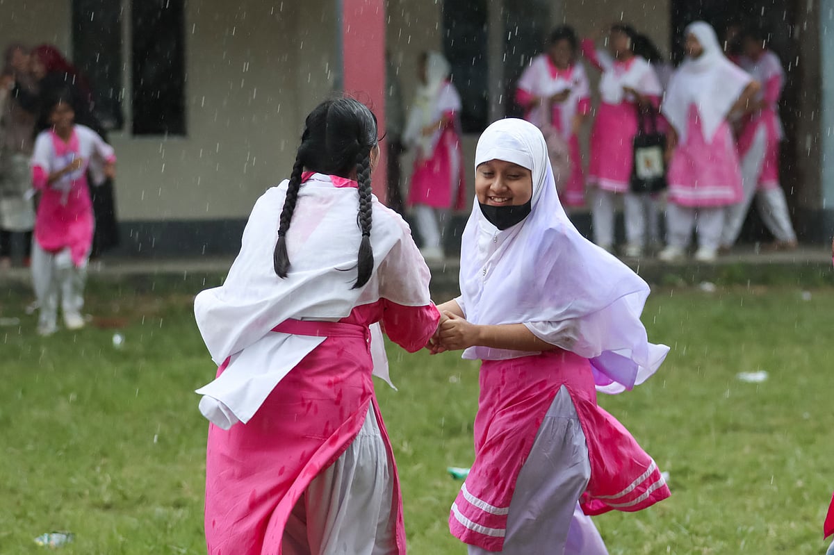 বৃষ্টি শুরু হলে এক সহপাঠী আরেক সহপাঠীকে মাঠে টেনে নিয়ে যাচ্ছে বৃষ্টিতে ভেজার জন্য