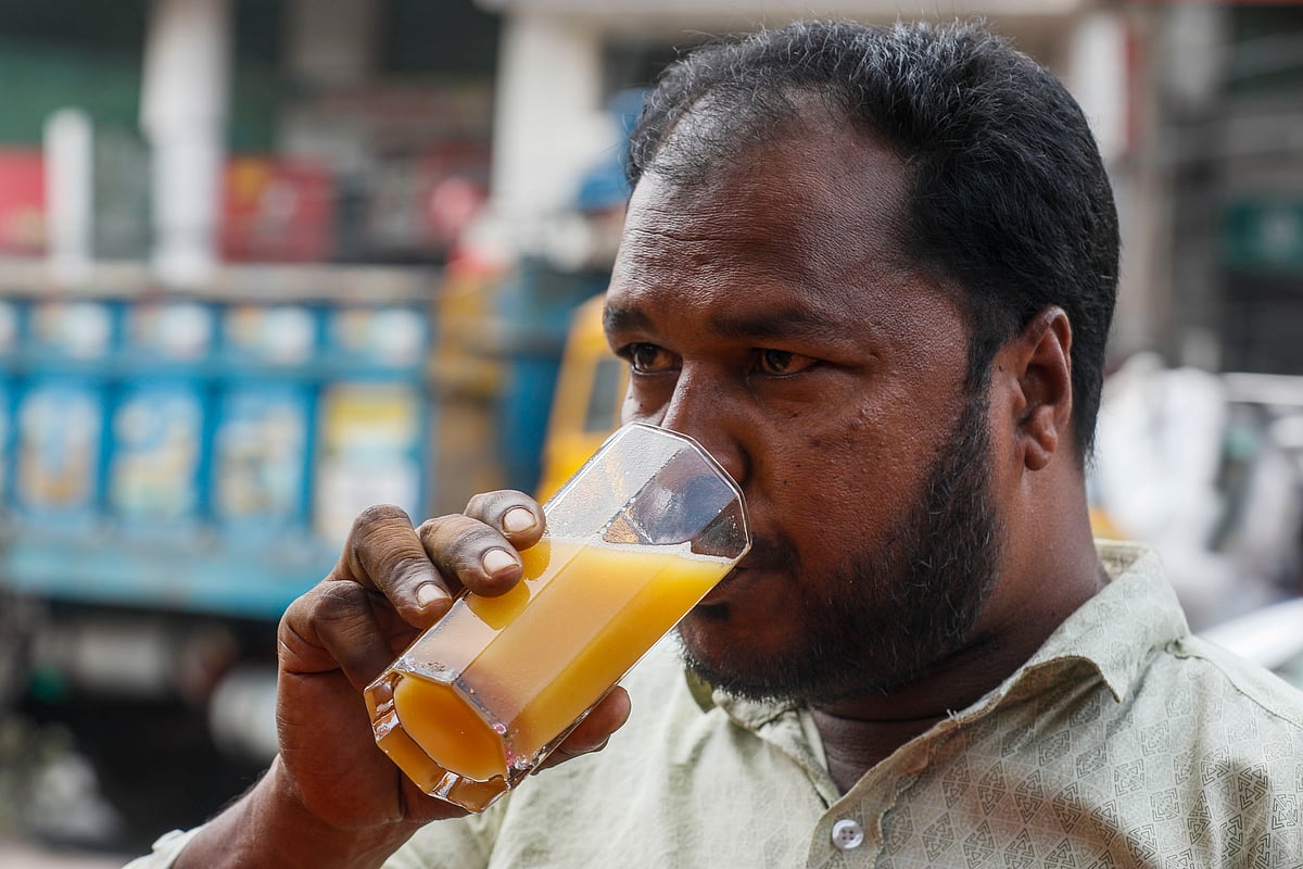 সড়কের পাশে দাঁড়িয়ে শরবত খাচ্ছেন একজন।