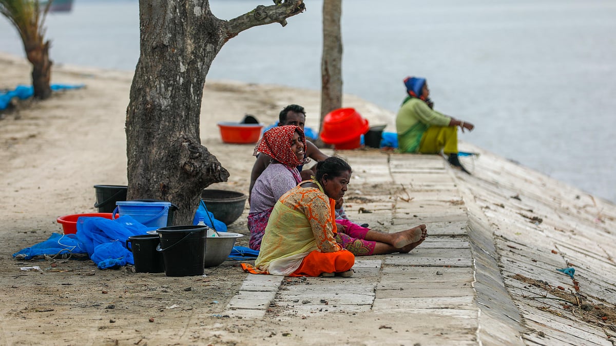 ভাটার অপেক্ষায় নদীর তীরে বসে আছেন রেণু আহরণকারীরা। 