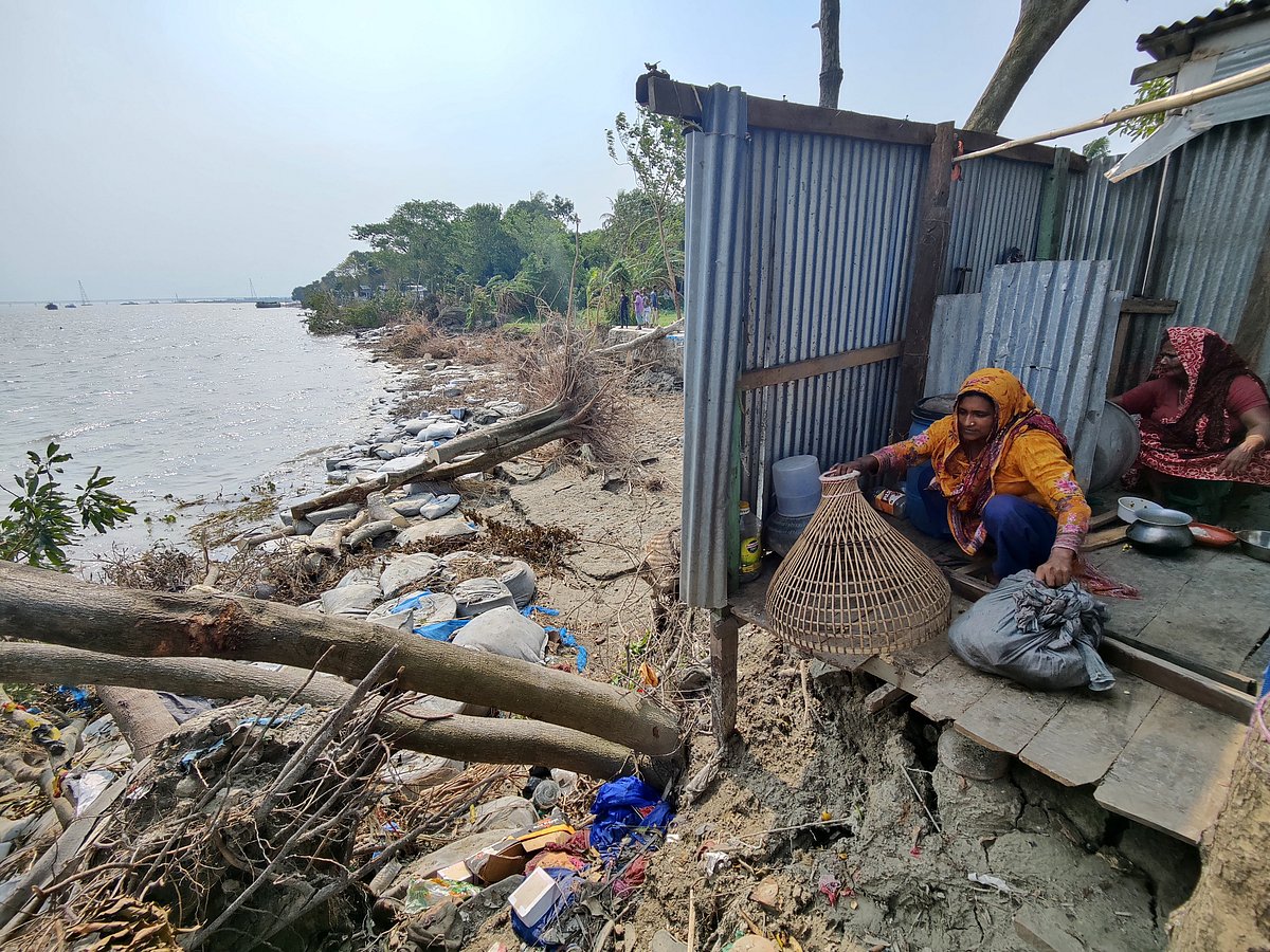 ঘোড়াদৌড় এলাকায় এই পরিবারটির বসতভিটার বেশির ভাগ অংশই নিয়ে গেছে পদ্মা নদী। চালাবিহীন রান্নাঘরে কাজ করছেন দুই নারী।