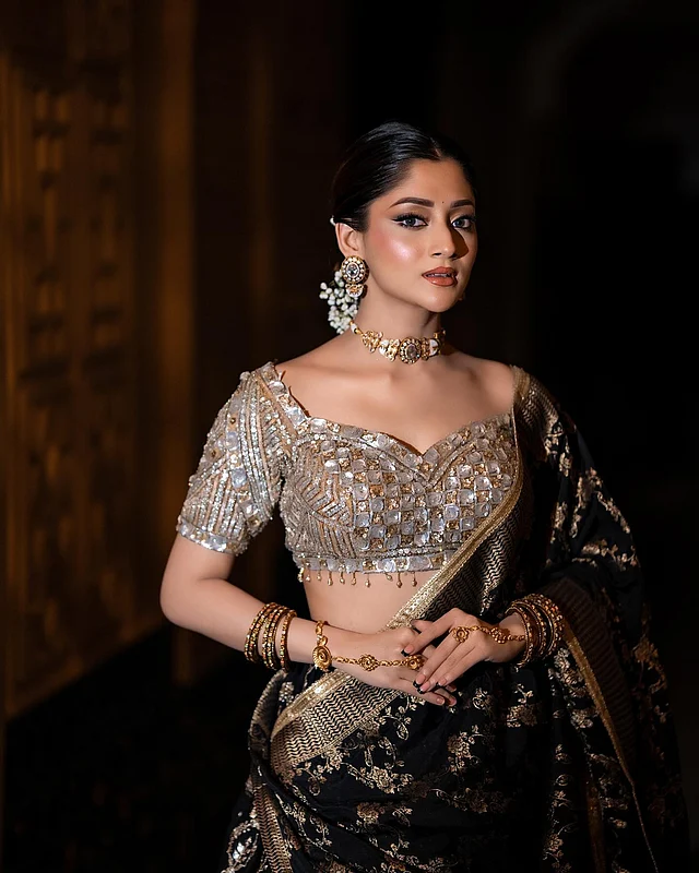 গভীর সুইটহার্ট নেকলাইনের চোলিটির ফিটিং এক কথায় চমৎকার। এতে ঝলমলে সোনালি রূপালি জরী ও এমব্রয়ডারির কাজ। নিচে ঝুলঝুলি দেওয়া আছে এই স্বল্প দৈর্ঘ্যের চোলিতে। 