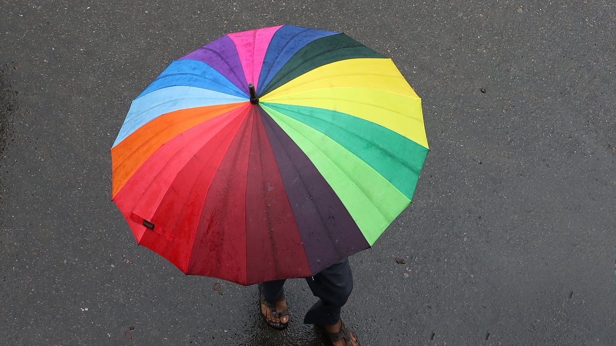 বন্দরবাজার এলাকায় রঙিন ছাতা হাতে পথ চলেছেন এক ব্যক্তি।