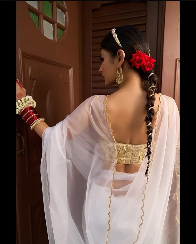 শাড়ির বর্ডারে ঢেউ খেলানো সোনালি বর্ডার আর চুলের লম্বা বেণিতেও সোনালি জরীর ফিতা। তাঁর এই বেণি অবশ্য নাগিণ সিরিয়ালের কথা মনে করিয়ে দিচ্ছে, যেটি তাঁকে পরিচিত করেছে শো বিজে। 
