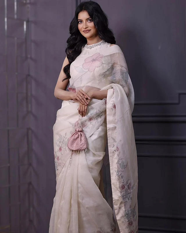সাদা ফ্লোরাল টিস্যু শাড়িতে তুষি। সঙ্গে পরেছেন হাইনেক ব্লাউজ। মাঝখানে সিঁথি করে পুরো চুল সেমিকার্ল করেছেন তিনি। সাজে রেখেছেন মিনিমাল কিন্তু গ্ল্যামছোঁয়া।