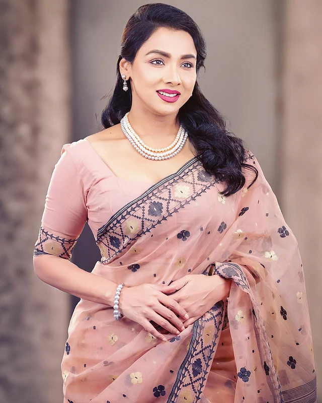 পিচরঙা জামদানিটি আড়ংয়ের। নান্দনিক নকশার ছিমছাম শাড়ির সঙ্গে রুনা খান পরেছেন কয়েক লহরের মুক্তার মালা ও ছোট ঝোলানো মুক্তার দুল। 