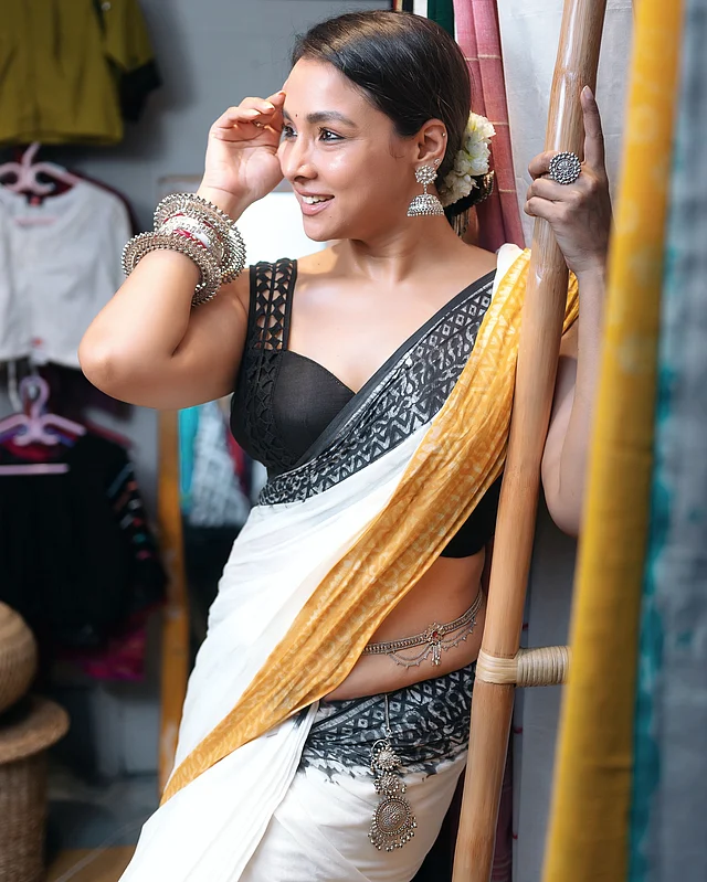 হলুদ ও কালো ডাই করা পাড়ের সাদা সুতির শাড়ির সঙ্গে ডিপ সুইটহার্ট নেকলাইনের কালো স্লিভলেস ব্লাউজে অভিনেত্রী 