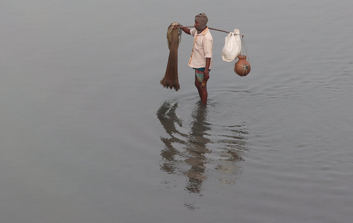মাছ ধরতে নদের পানিতে নেমেছেন জেলে শুকারু দাস।