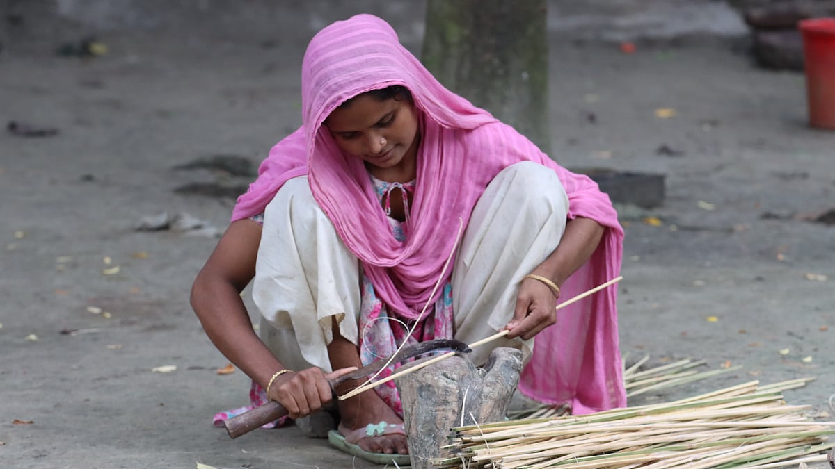 বাঁশের শলা কাটছেন এক গৃহবধূ
