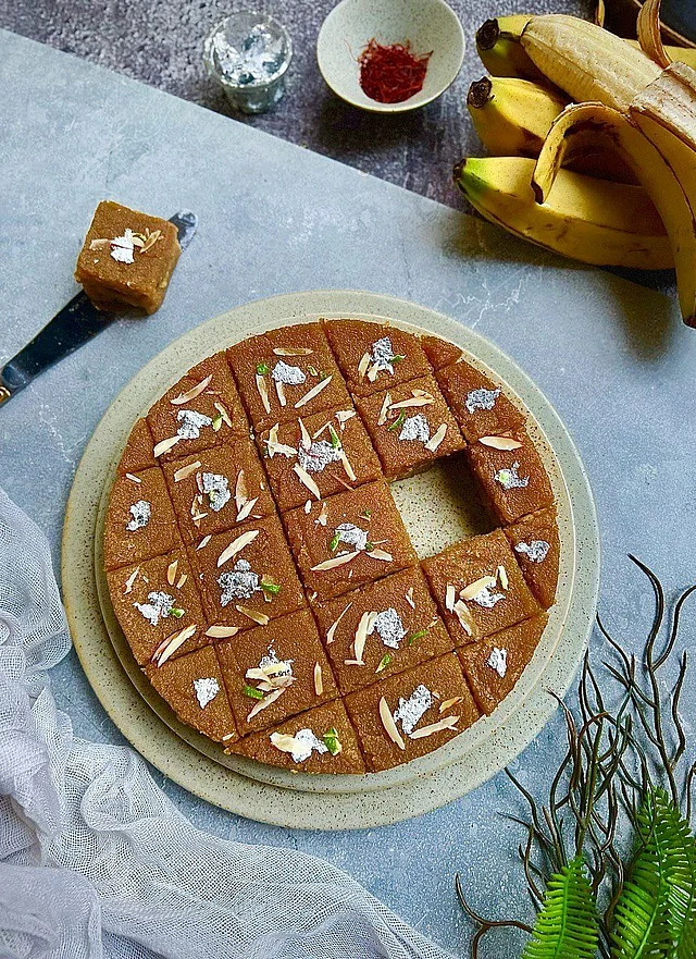 কলা পেস্ট করে নিন। এবার গুড়, নারকেল, গুঁড়া দুধ, মাখন বা ঘিয়ে ভেজে নেওয়া পোলাওর চালের গুঁড়া, দারুচিনি গুঁড়া, বাদাম কুচি এক এক করে সব মিশিয়ে রান্না করুন আঠালোভাব হওয়া পর্যন্ত।