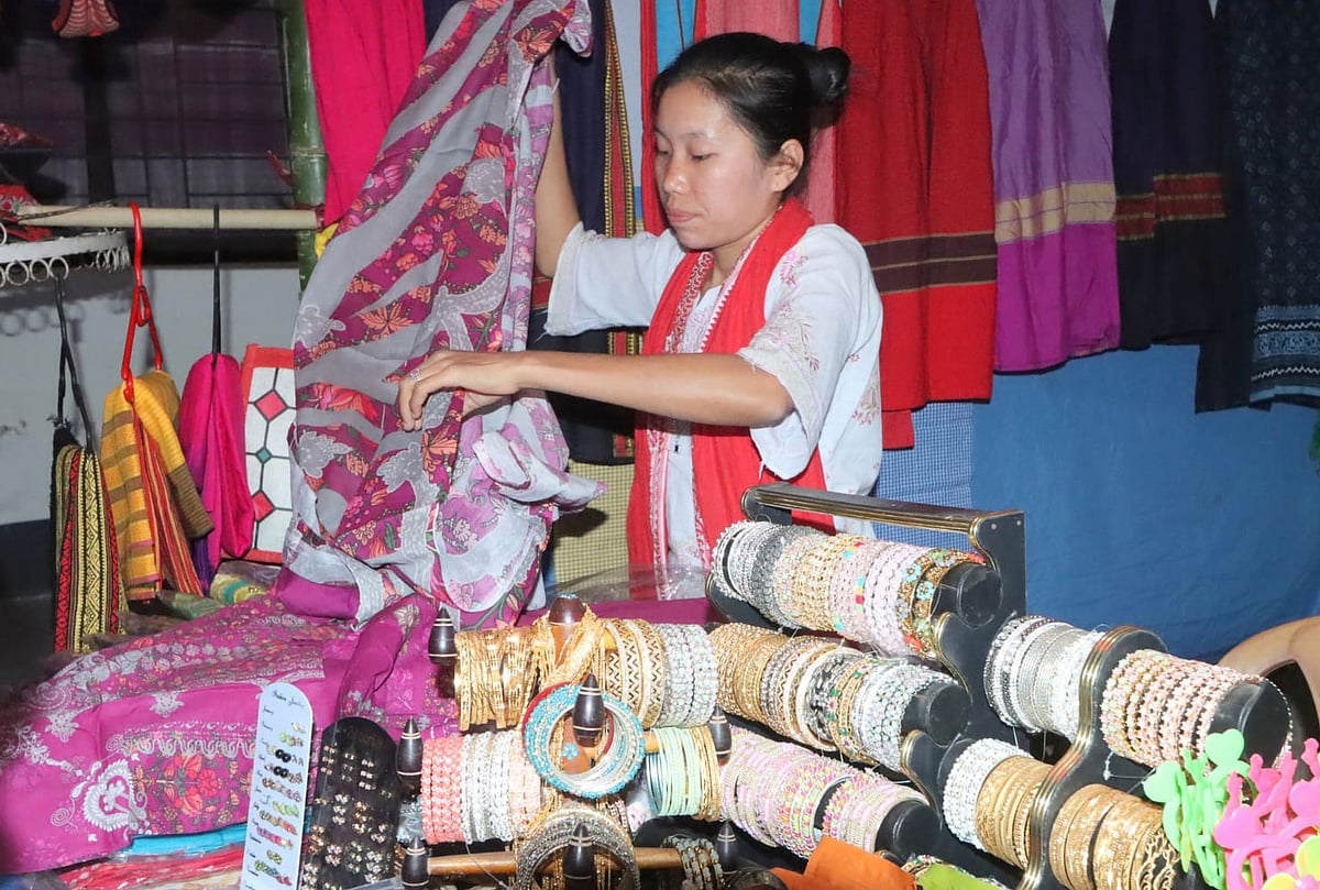 স্টলে পোশাক গুছিয়ে রাখছেন এক নারী বিক্রেতা