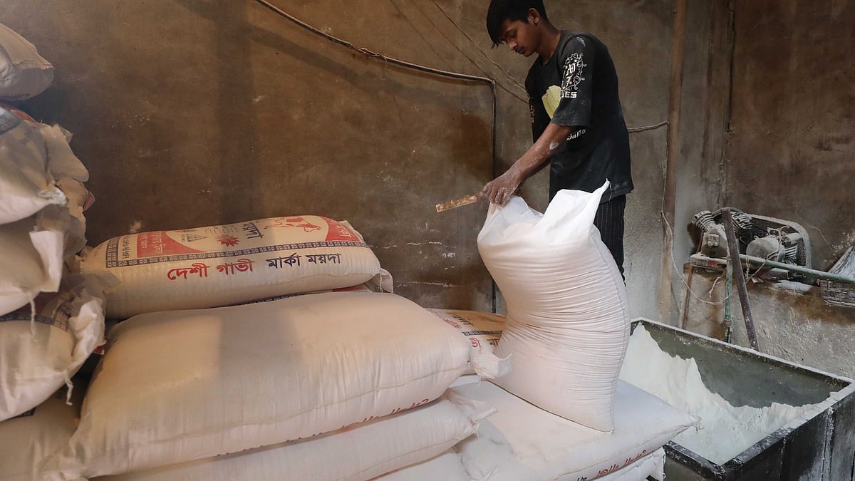 সেমাই উৎপাদনের জন্য বস্তা থেকে ময়দা বের করছেন একজন শ্রমিক 