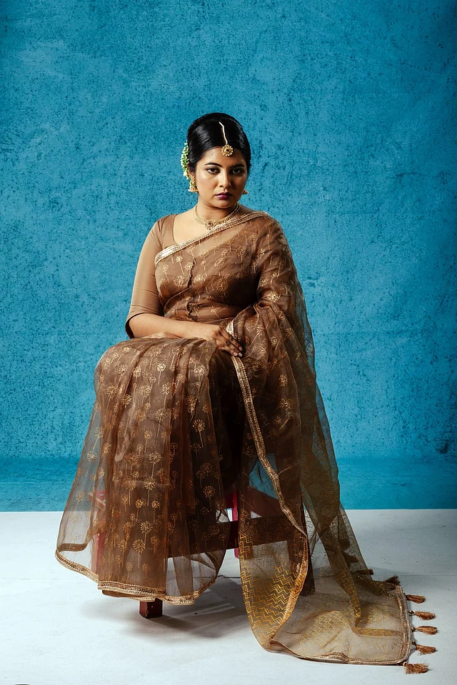 কফি ব্রাউন এই শাড়িতে সোনালি ব্লকের প্রিন্টে ফুলেল মোটিফ প্রাধান্য পেয়েছে।পাড়কে আকর্ষণীয় করতে ব্যবহার করা হয়েছে সোনালি সিকুইন লেইস।  