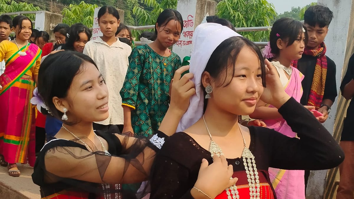 এক তরুণীকে ঐতিহ্যবাহী খবং পড়িয়ে দিচ্ছে আরেক তরুণী