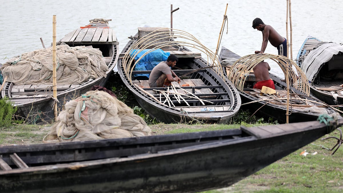 ঘাটে রাখা নৌকার ছই তৈরি করছেন কয়েকজন জেলে