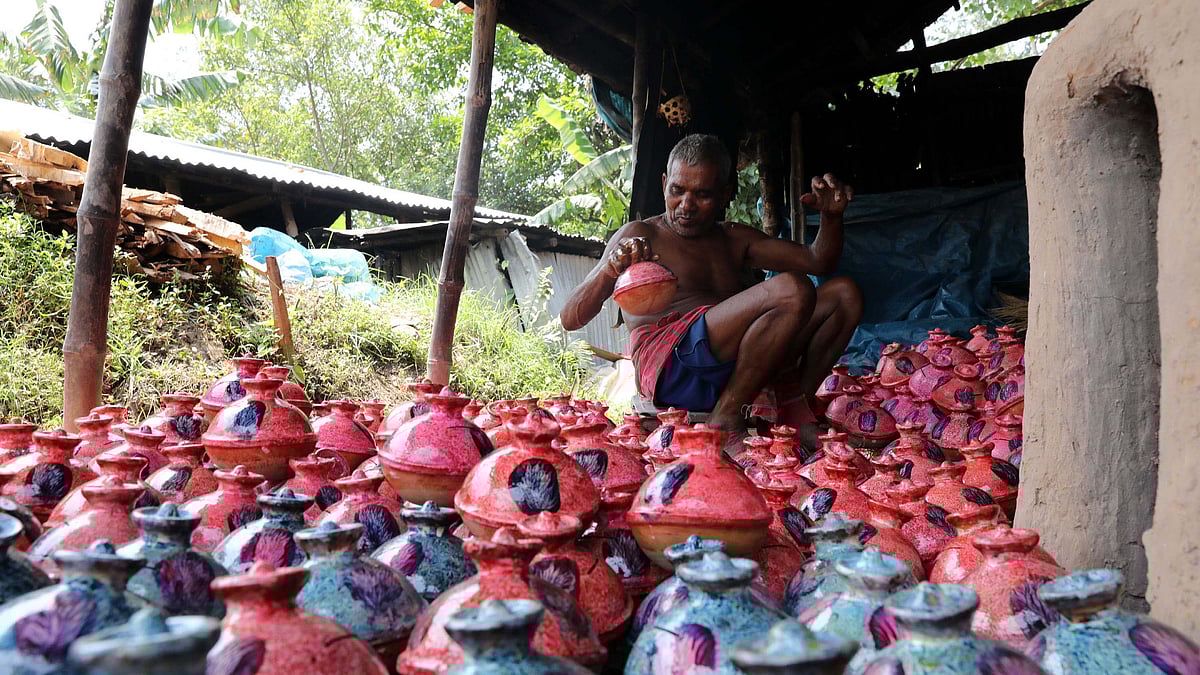 ঘরের এক পাশে বসে নিজ হাতে তৈরি মাটির ব্যাংক রাঙিয়ে তুলছেন