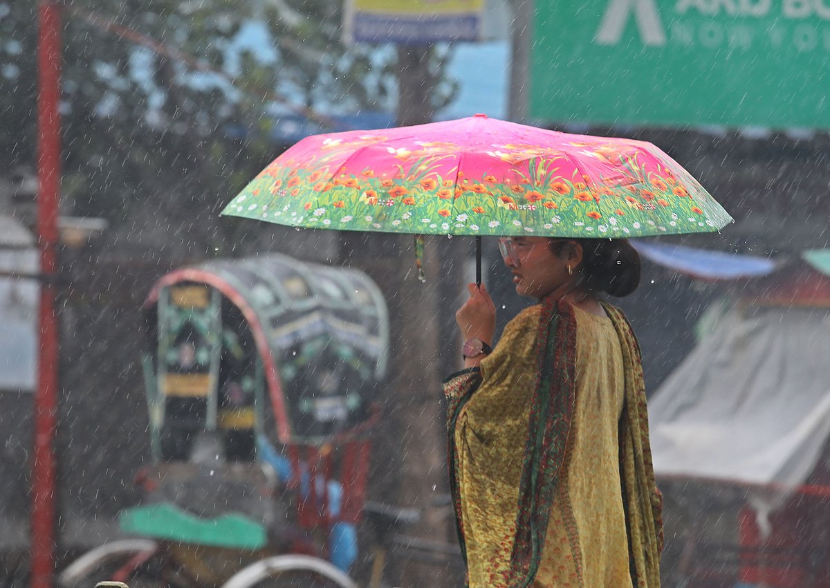 বৃষ্টির মধ্যে ছাতা নিয়ে বের হয়েছেন একজন তরুণী। 