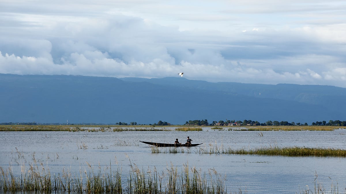 আকাশে মেঘের ভেলা, উড়ছে পাখি। পাহাড়ের কোলঘেঁষা হাওরে চলছে নৌকা