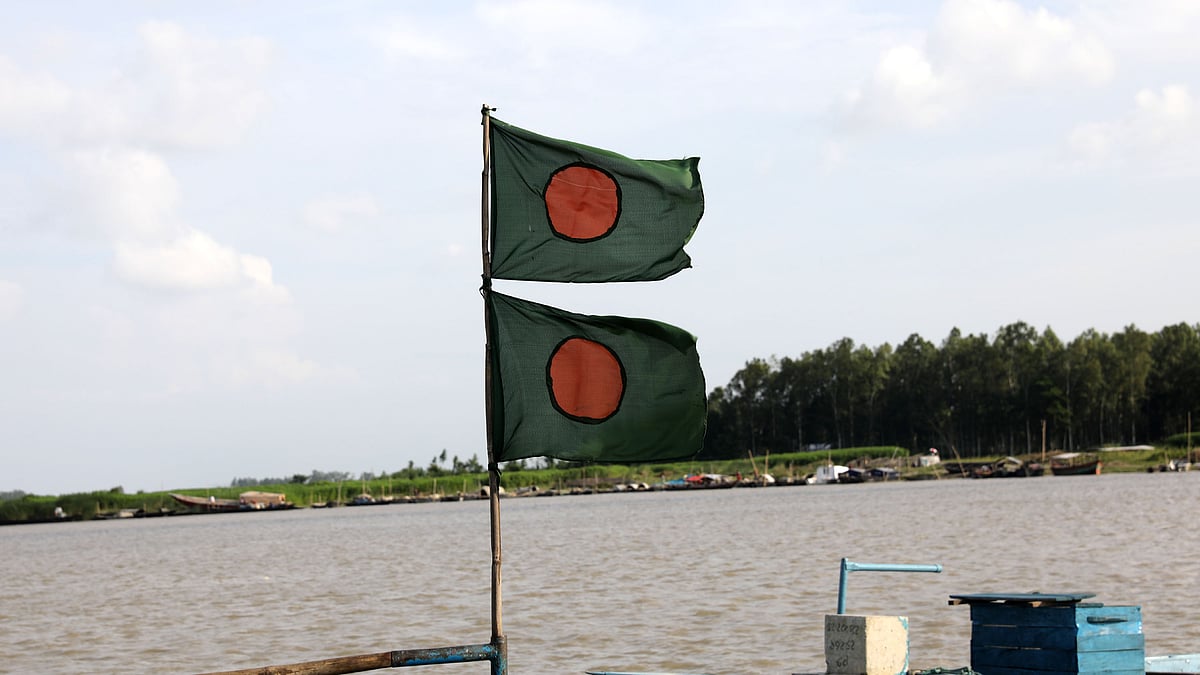 খেয়াঘাটে বাঁধা নৌকার মাথায় উড়ছে লাল-সবুজের পতাকা।