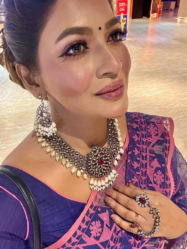 নেভি ব্লু-গোলাপি জামদানিতে বাঁধন। সঙ্গে পরেছেন ভারী, ব্ল্যাক অ্যান্টিক কালার কোটেড গয়না। আর্টিফিশিয়াল পার্ল ও পুঁতির কাজের এই গয়নার সবচেয়ে নজরকাড়া দিক হলো সেটের মধ্যে থাকা স্টিমুলেটেড রিয়েল রুবি স্টোন। এ সেটের সঙ্গে মিলিয়ে বাঁধনের পরা চোখজুড়ানো আংটিটিও আলাদা করে নজর কাড়ে। ২০১৫ সালে গ্লুড টুগেদার ডিজাইন করা এই আংটি ব্র্যান্ডের অন্যতম বেস্ট সেলিং পণ্য।
