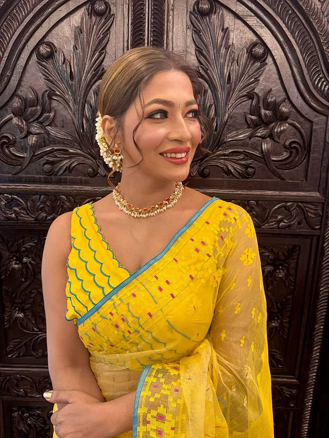নীল বর্ডার দেওয়া উজ্জ্বল হলুদ জামদানিতে বাঁধনের লুক যেন আধুনিকতায় মোড়ানো ঐতিহ্যের প্রতিচ্ছবি। জুটি হয়েছে স্লিভলেস ব্লাউজ। তাঁর পুরো লুকের সঙ্গে দারুণভাবে মানিয়ে গেছে পদ্মফুল মোটিফে তৈরি স্টেটমেন্ট জুয়েলারিটি। 