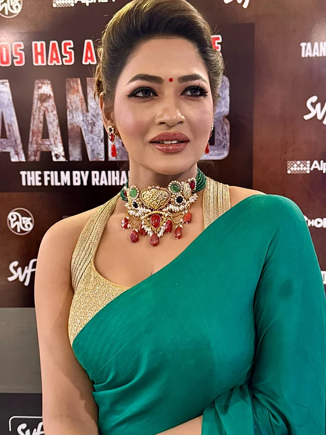 অভিনেত্রীর পরা একরঙা টিল গ্রিন শাড়ির সঙ্গে নিঃসন্দেহে মানানসই এই স্টেটমেন্ট জুয়েলারি। ভারী পাথর ও পার্ল বিডসে তৈরি গয়নাটি বেশ নজরকাড়া। গ্লুড টুগেদারের এই গয়না মূলত ব্রাইডাল অনুষ্ঠানের জন্য ডিজাইন করা হলেও বাঁধনের মতো করে যাঁরা গ্ল্যামার আর সাবলীলতা একসঙ্গে বহন করতে পারেন, তাঁদের জন্যও আদর্শ। ২১ ক্যারেট গোল্ড প্লেটেড এই মেটাল সেটে রয়েছে মিক্সড শেডের আর্টিফিশিয়াল আকিক স্টোন ও পুঁতির সূক্ষ্ম কাজ। ভারী গলার সেটের সঙ্গে ভারসাম্য রাখতে কানের দুল রাখা হয়েছে ছোট আকারের, যা পুরো লুকে এনেছে ভারসাম্যপূর্ণ অথচ রাজকীয় আভিজাত্য।