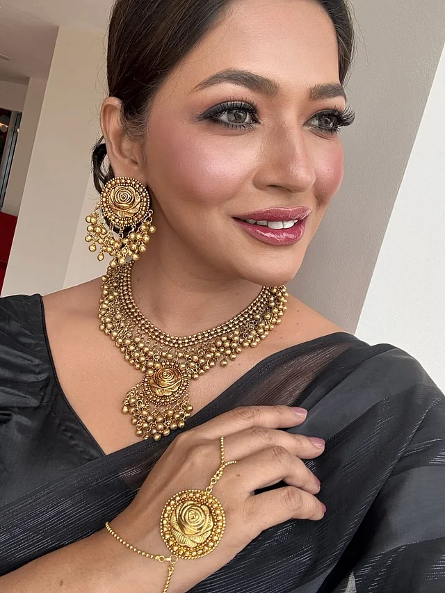 বাঁধনের এই লুকের মূল আকর্ষণ হলো জুয়েলারি—যেটি তৈরি হয়েছে নকশা মোটিফে গোলাপ ফুলকে কেন্দ্র করে। ফুলের প্রতীকী সৌন্দর্য আর নারীত্বের ছোঁয়া মিলেছে এ গয়নার খুঁটিনাটিতে। মেটাল আর বল স্ট্রাকচারে তৈরি সেটটি মোনোক্রম পোশাকের সঙ্গে বেশ মানিয়ে যাবে। অভিনেত্রী একরঙা কালো শাড়ির সঙ্গে এ গয়না পরেছেন। আর হাতে পরেছেন ফুলেল রতনচূড়।
