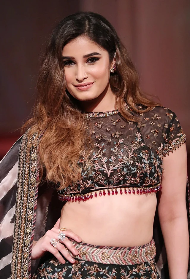 মা রাভিনার ধারালো মুখশ্রী আর গ্রেসে অনন্যা রাশা পরেছেন কপার জরির ঝমকালো লেহেঙ্গা। বোটনেক টপে লাল ঝোলানো পাথরের বর্ডার নজর কাড়ছে