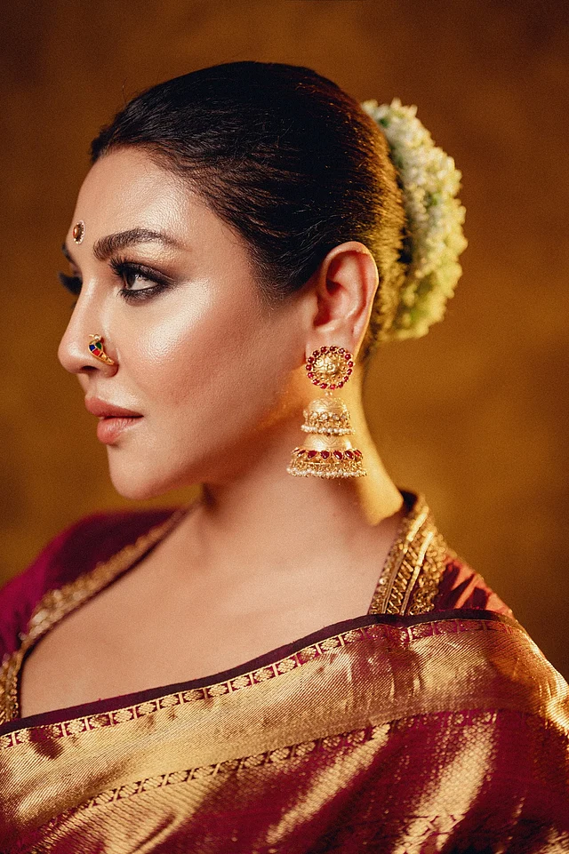 মাঝসিঁথি করে টেনে বাঁধা খোঁপায় সাদা ফুলের গাজরা। ঝুমকার লুকে এসেছে ঐতিহ্যবাহী আমেজ