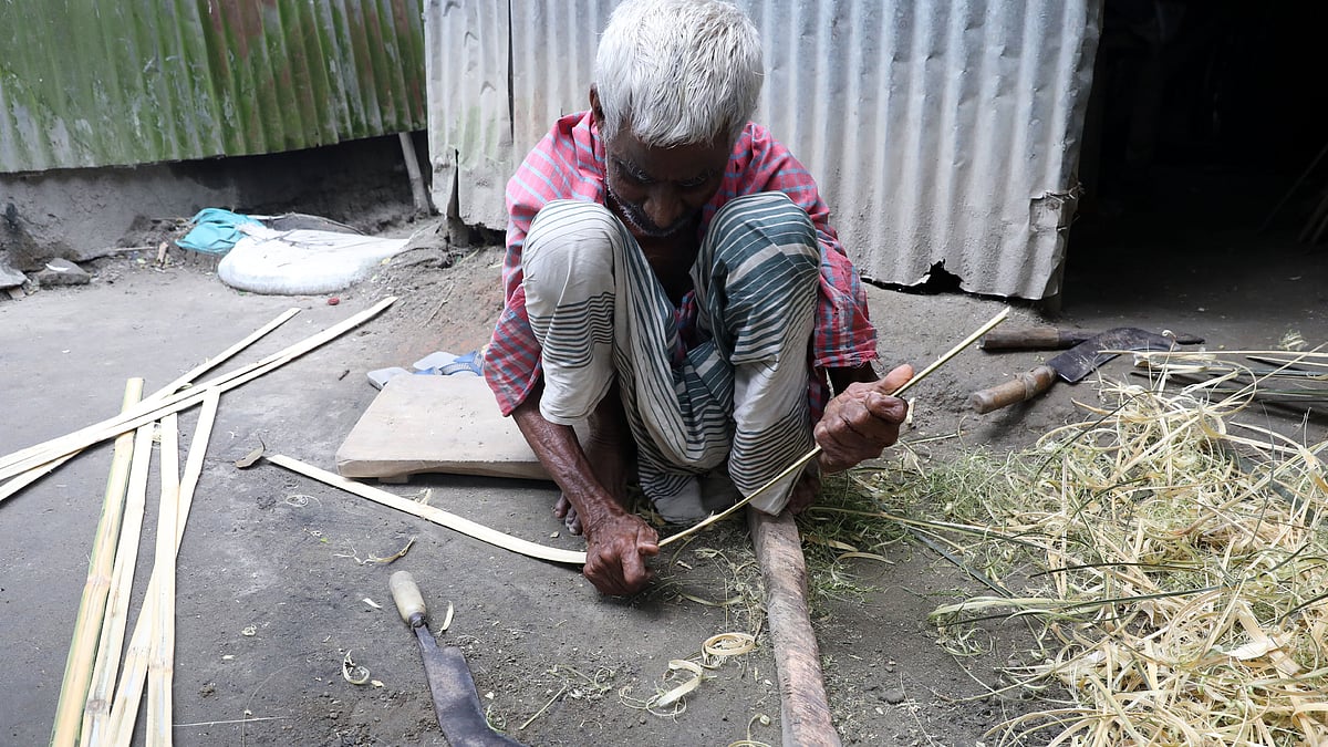 বাড়ির উঠানে বসে বাঁশের তেমাল তুলছেন জ্ঞানেন্দ্রনাথ দাস