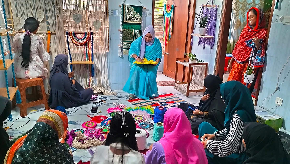 দিনাজপুর শহরের পশ্চিম রামনগর এলাকায় চতুর্ভুজের কারখানায় ড্রিমক্যাচার তৈরি করছেন নারীরা। পাশে বসে দেখিয়ে দিচ্ছেন প্রতিষ্ঠানের পরিচালক শামীমা নাছরিন। সম্প্রতি তোলা ছবিছবি: প্রথম আলো