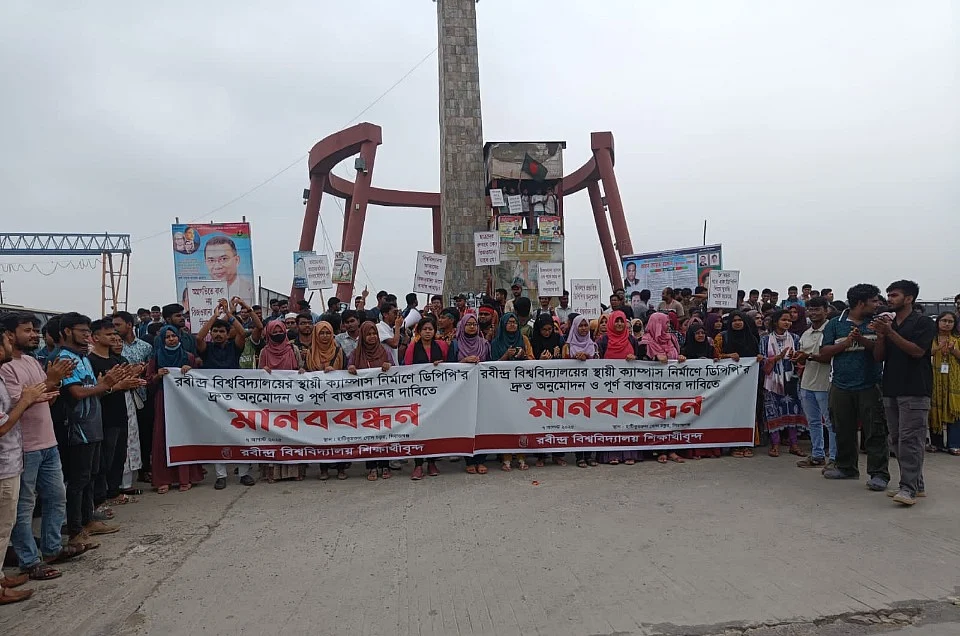 সিরাজগঞ্জের শাহজাদপুরে রবীন্দ্র বিশ্ববিদ্যালয়ের স্থায়ী ক্যাম্পাস নির্মাণ প্রকল্পের ডিপিপি দ্রুত অনুমোদন ও বাস্তবায়নের শিক্ষার্থীদের মানববন্ধন। আজ দুপুর ১২টার দিকে ঢাকা-বগুড়া-নগরবাড়ী মহাসড়কের হাটিকুমরুল গোলচত্বর এলাকায়ছবি: প্রথম আলো