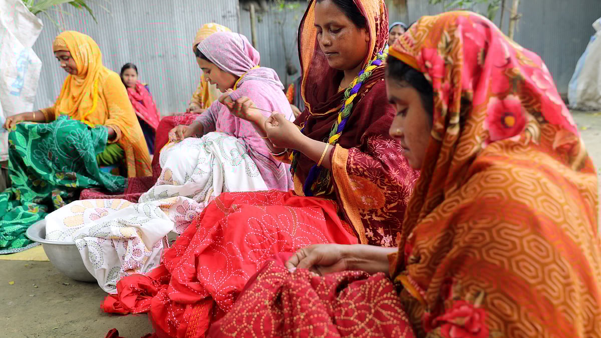 বাড়ির উঠানে বসে নকশিকাঁথা বোনায় ব্যস্ত কয়েকজন নারী