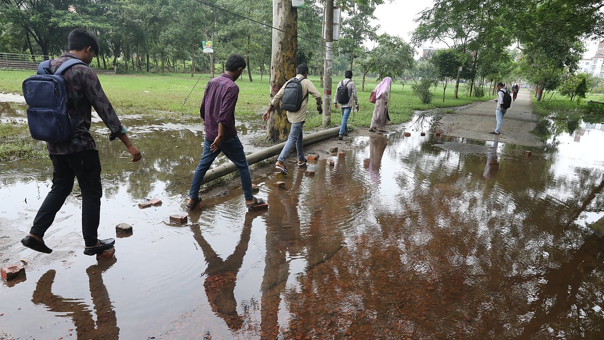 জমে থাকা পানি পেরিয়ে ক্লাসে যাচ্ছেন শিক্ষার্থীরা।