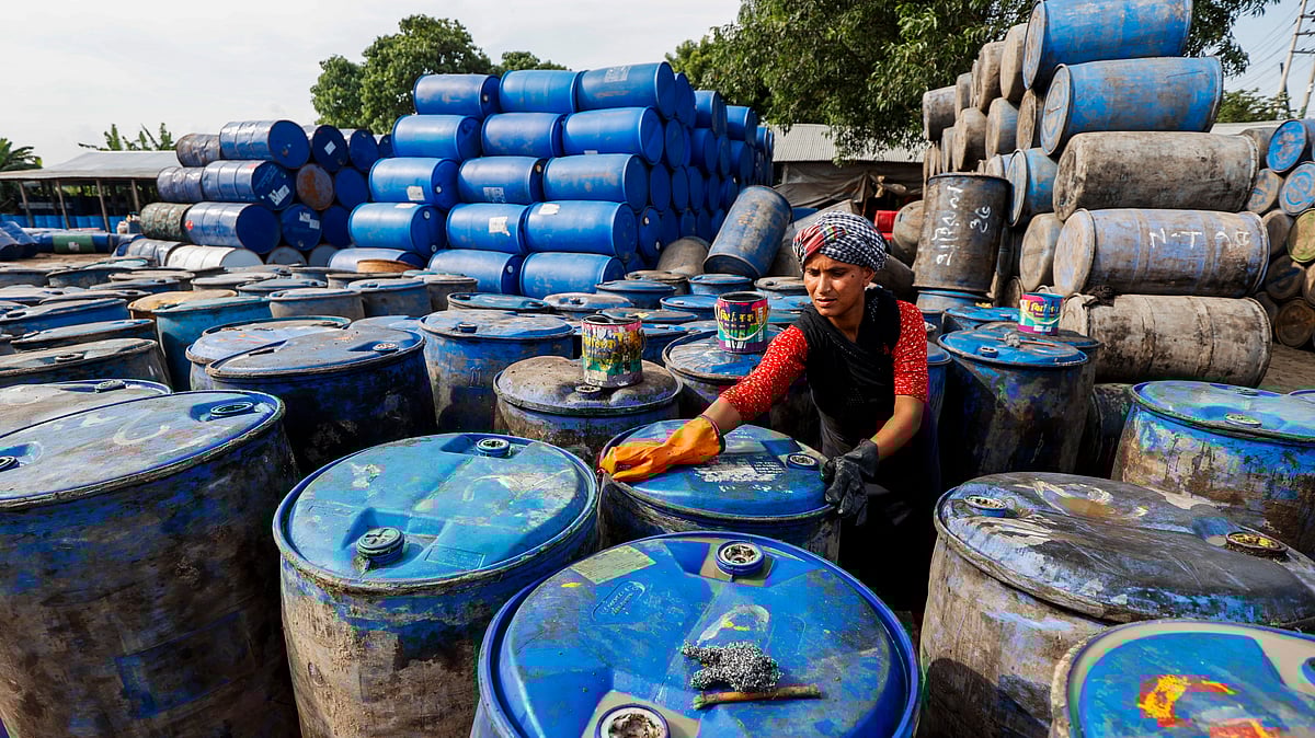 পুরোনো প্লাস্টিকের ড্রাম ধুয়ে পরিষ্কার করছেন এক নারী