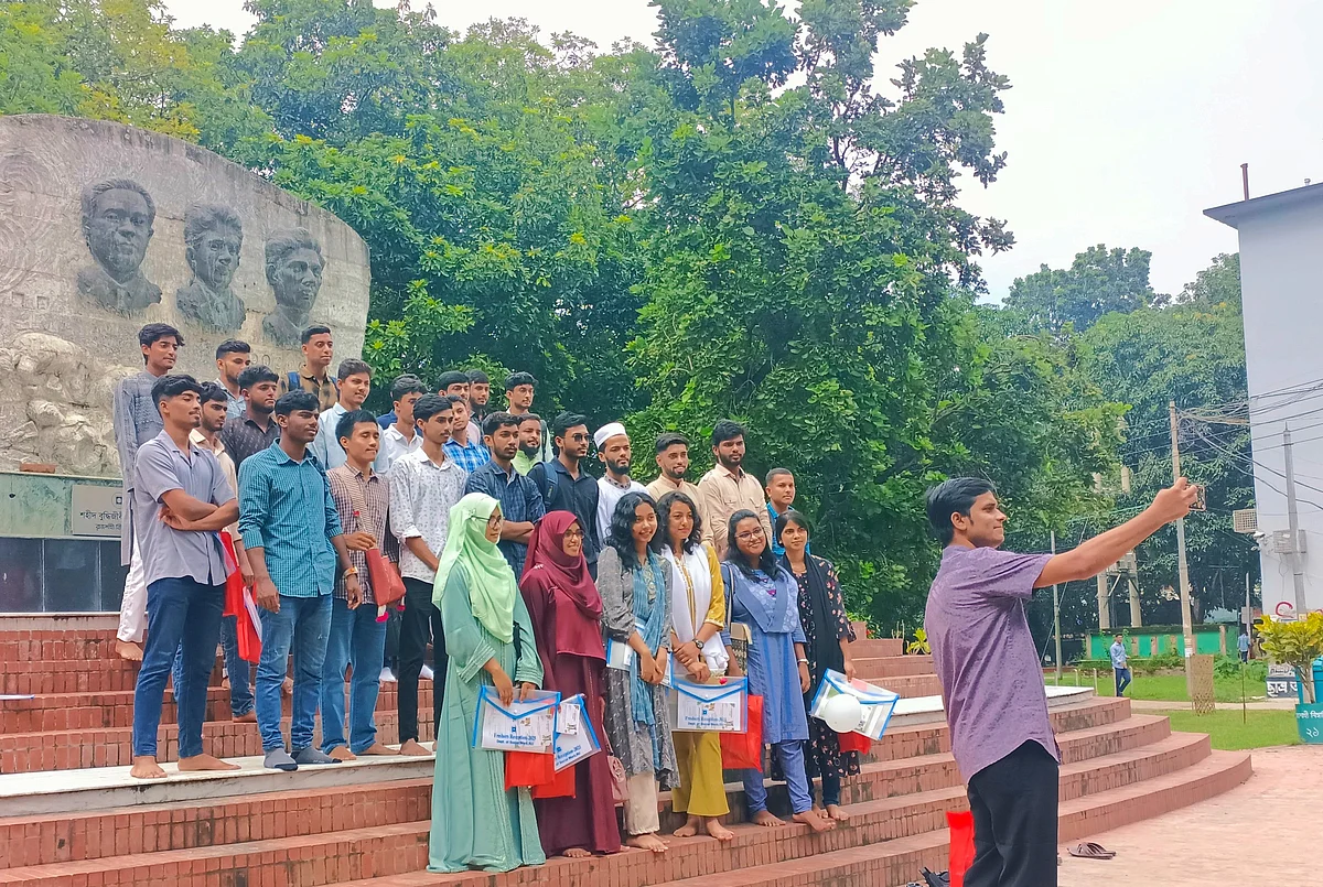 নবীন শিক্ষার্থীরা দলবেঁধে ছবি তুলছেন। আজ রোববার দুপুরে বিশ্ববিদ্যালয়ের বুদ্ধিজীবী স্মৃতিফলক চত্বরেছবি: প্রথম আলো