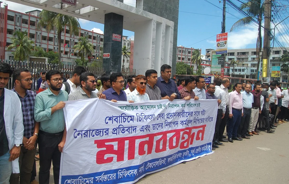 শের-ই-বাংলা মেডিকেল কলেজ হাসপাতালের চিকিৎসক-কর্মচারীরা হামলাকারীদের গ্রেপ্তার ও নিরাপদ কর্মপরিবেশের দাবিতে মানববন্ধন করেন। আজ সোমবার দুপুরে হাসপাতালের মূল ফটকের সামনেছবি: প্রথম আলো