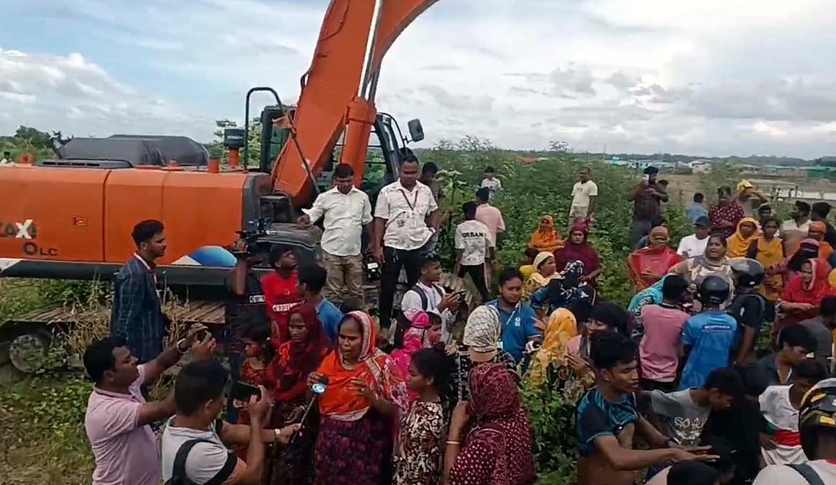 কক্সবাজার শহরের বাঁকখালী নদীর তীর দখল করে নির্মিত অবৈধ ঘরবাড়ির উচ্ছেদ ঠেকাতে দখলদার লোকজন খননযন্ত্র ঘিরে বিক্ষোভ করেন। আজ দুপুরে নদীর পেশকারপাড়া অংশেছবি: প্রথম আলো