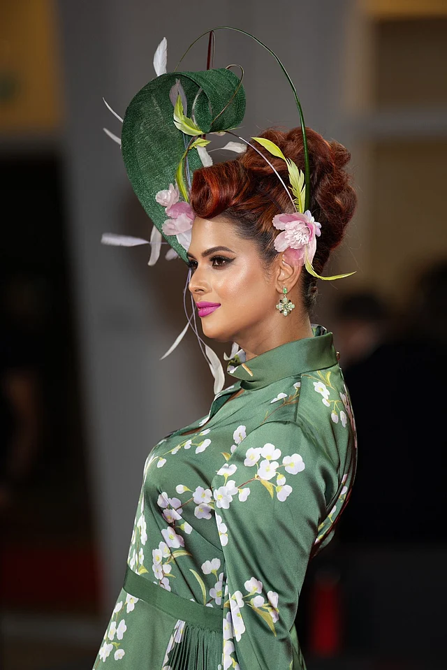 বোল্ড আই লুক, গোলাপি লিপকালার আর ফ্লোরাল স্টেটমেন্ট দুলে সেজেছেন প্রিয়তি। তবে সঙ্গে সবচেয়ে বেশি নজর কাড়ছে মাথায় পরা স্টেটমেন্ট হেডপিসটি। সবুজ কার্ভি লিফ-স্ট্রাকচার, গোলাপি ফুল আর পালকের সমন্বয়ে তৈরি এই হেডপিস ডিজাইন করেছেন আইরিশ ডিজাইনার ফিওনা রাফটার।