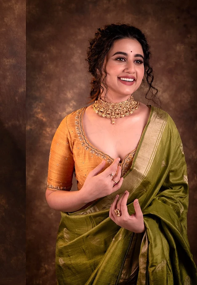 ছোট লাল টিপ, হালকা ব্রিক রেড লিপস, কোঁকড়া চুলের স্ট্র্যান্ডস আর ভারী চোকারে মোহনীয় লাগছে তাঁকে