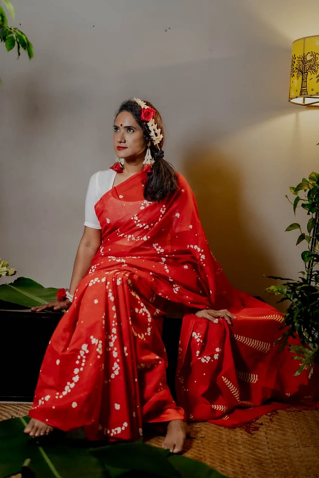 এই গাজরা ডিজাইনটি কটন রুটসের সিগনেচার। বেলি ফুলের মালা প্রাণিত এই নকশা আছে শাড়িটির পুরো জমিন জুড়ে। আর আঁচলে সোনালি ব্লকের ছাপ।