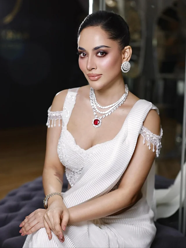 টেনে বাঁধা স্লিক আপডু স্টাইল দারুণ মানিয়েছে এই লুকে। সঙ্গে তমা পরেছেন সাদা পাথরের বড় টপ। তিন লহরের নেকপিসে লাল পাথরটি নজর কাড়ছে। 