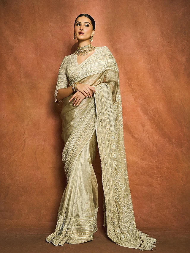 চুল বাঁধা পরিপাটি বান, গলায় সবুজ-সোনালি গয়না। এই বৈপরীত্যই শাড়ির সৌন্দর্যকে বাড়িয়ে তোলে। তার মুখে ছিল মৃদু গ্ল্যাম, আর পুরো উপস্থিতি জুড়ে ছিল পরিমিত শোভা