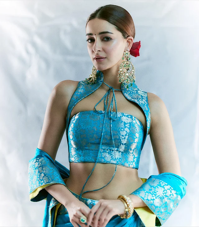 ব্লাউজের ডিজাইনটি ফিউশন স্টাইলের। ক্ল্যাসিক সিলুয়েটের বদলে বেছে নেওয়া হয়েছে স্লিক হল্টার স্টাইল ব্লাউজ, যার কি-হোল টাই-আপ নেকলাইন আছে। এই শাড়ি-গাউন লুক বেনারসির ঐতিহ্যকে রিচ স্টাইলিংয়ের মাধ্যমে নতুনভাবে উপস্থাপন করেছেন অনন্যা। পরিপাটি ড্রেপ এবং আধুনিক ব্লাউজের কনট্রাস্ট লুকটিকে করেছে সবচেয়ে আলাদা। 