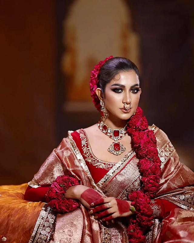 ঝলমলে গোল্ডেন-লাল ব্রাইডাল পোশাকের সঙ্গে লাল গোলাপের সাজে দেখা যাচ্ছে এই মডেলকে