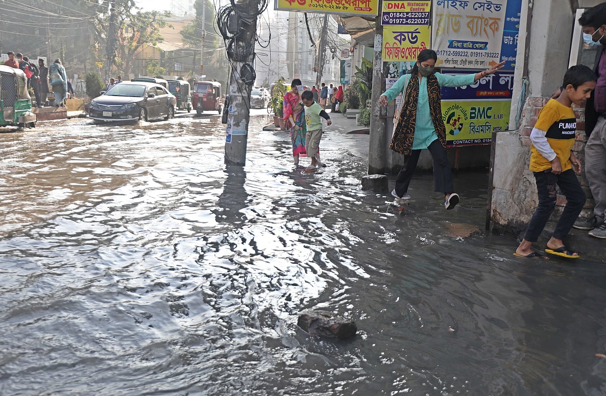 ময়লা পানি থেকে বাঁচতে লাফ দিয়ে রাস্তা পার হচ্ছেন এক নারী। 