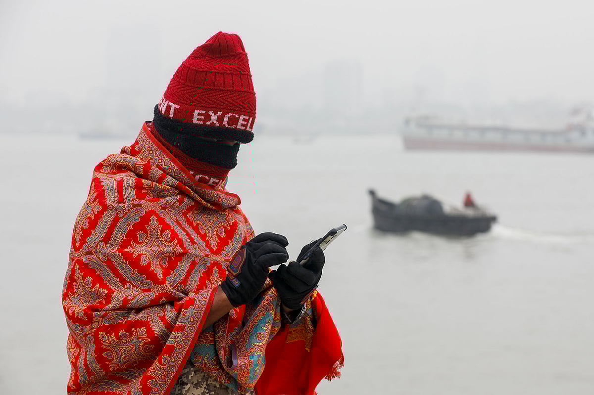 কর্ণফুলী নদীর তীরে ঠান্ডায় জবুথবু হয়ে মুঠোফোনে কারও সঙ্গে যোগাযোগ করছেন এই ব্যক্তি 