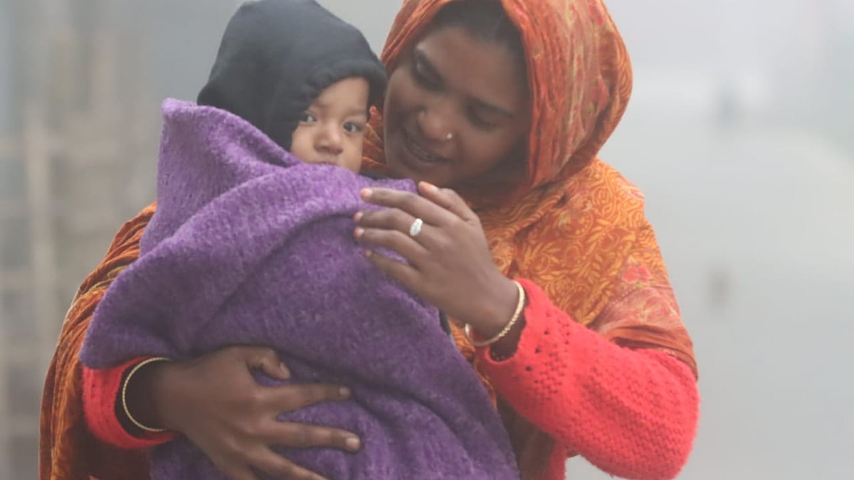 শিশুকে ঘরের বাইরে নিতে কম্বল পেঁচিয়ে নিচ্ছেন মা
