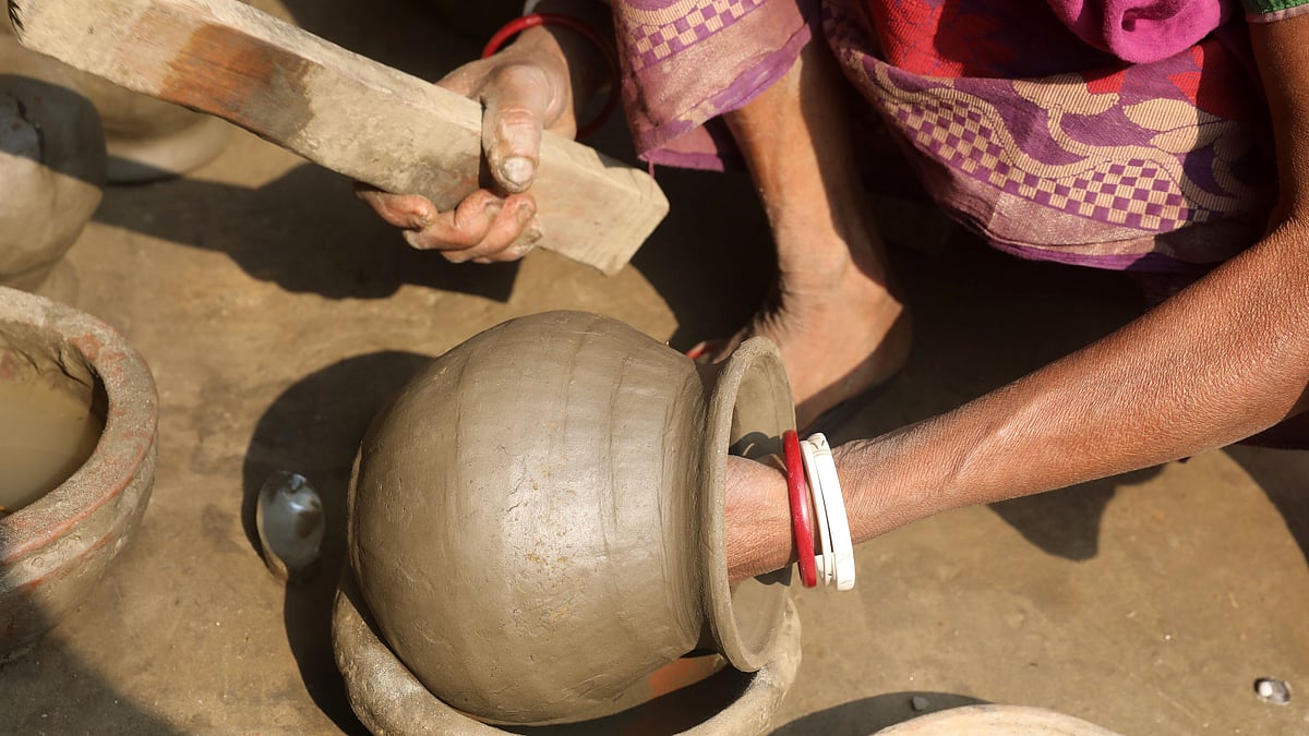 বাড়ির উঠানে বসে দইয়ের হাঁড়ি তৈরি করছেন দেবী রানী পাল